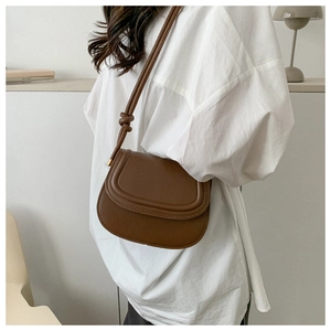 Detail of dark brown leather saddle bag with unique knotted strap and sleek flap design