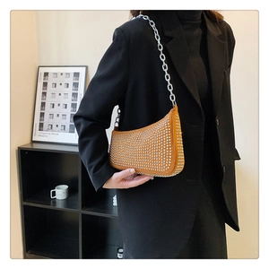 Close-up of orange rivet bag worn with a black blazer showing metallic chain details