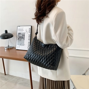 Chic black quilted bucket bag with gold accents shown being worn over the shoulder