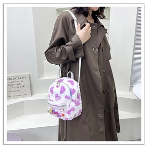 Détail d'un sac à dos en peluche blanc avec motifs coeurs violets et zip en perle