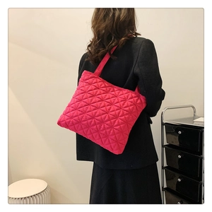 Detail of rose pink quilted tote bag with star pattern stitching worn by model