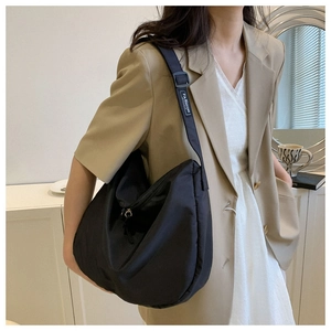 Gros plan du sac hobo matelassé noir avec bandoulière réglable sur blazer beige