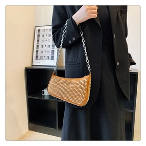 Detail of orange crossbody bag with silver studs and chain strap on a model
