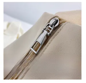 Detail shot of the smooth silver metal zipper and canvas fabric on the beige shoulder bag