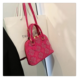 Détail du sac en daim fuchsia avec cercles de clous argentés et fermeture éclair dorée