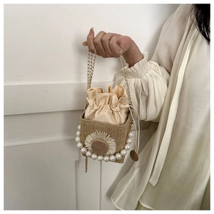 Detail of straw woven bucket bag featuring pearl handle and sunflower decoration