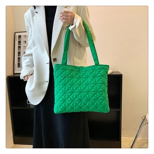 Vibrant green quilted tote bag with geometric stitching carried by a model
