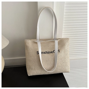 Detailed texture of woven straw tote bag featuring SunshineGirl text and PU leather handles