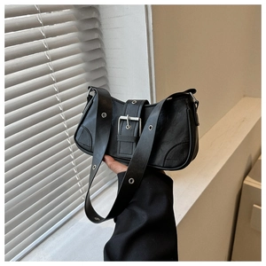 Detail of black leather square bag with large buckle strap and metal eyelet shoulder strap