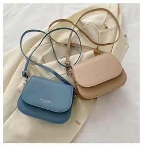 Flat lay of small PU leather crossbody bags in blue and beige with silver logo