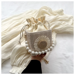 Detailed close-up of handmade woven straw bag with pearl handle and 3D daisy flower deco