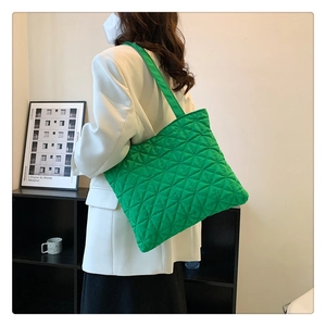 Detail of bright green quilted tote bag with diamond stitching shown as a shoulder bag