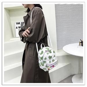 Détail du sac à dos en peluche blanche à cœurs verts, poche PVC et zip perlé
