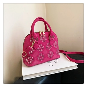 Détail du sac à main en daim fuchsia avec clous argentés et finitions métalliques dorées