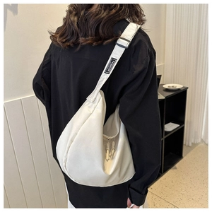 Détail du sac hobo blanc cassé avec large bandoulière et étiquette logo FASHION