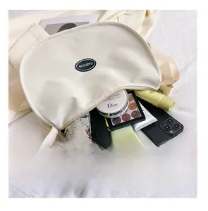 Detail presentation showing the spacious interior of the beige crescent oxford crossbody bag
