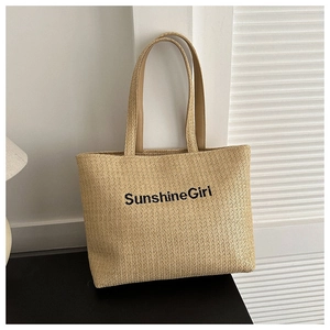 Detail of handwoven canvas tote bag with Sunshine Girl embroidery on neutral straw texture