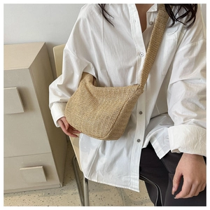 Detailed close-up of a large woven straw crossbody bag with wide strap for summer casual wear