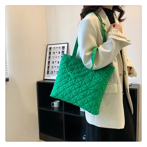 Detailed view of a bright green quilted tote bag with a soft puffy texture and large capacity
