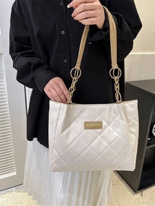 White quilted tote bag with gold chain strap and fashion label shown on a model