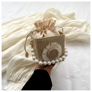 Detail of woven straw bag with large white daisy, pearl handle, and drawstring lining