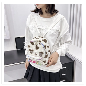 Détail du sac à dos en peluche à motif léopard cœur avec poche transparente et pompons colorés