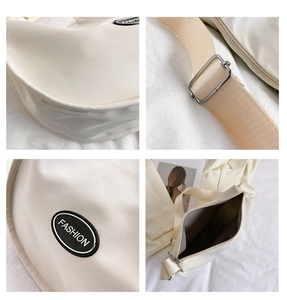 Detail view of beige half-moon crossbody bag with wide shoulder strap and metal buckle