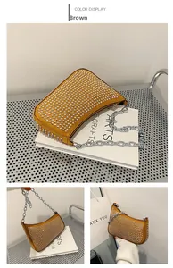 Close-up of brown suede underarm bag with silver rivet studs and chunky metal chain