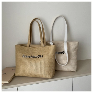 Close-up of woven straw tote bags with SunshineGirl embroidery and leather handles