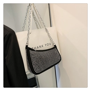 Detail of black studded underarm bag with silver rivets and metallic chain strap