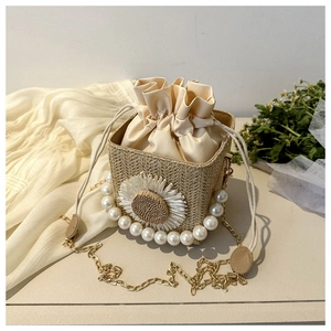 Detail of woven straw bucket bag with sunflower decor, pearls and gold chain strap
