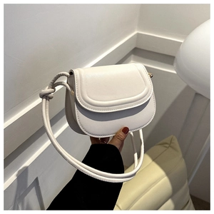Close-up of white saddle bag with knotted shoulder strap detail and leather texture