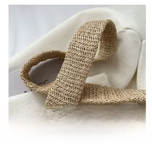 Close-up of the natural woven strap with herringbone pattern on a straw tote bag
