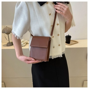 Gros plan d'un petit sac bandoulière en cuir marron porté par un mannequin en intérieur