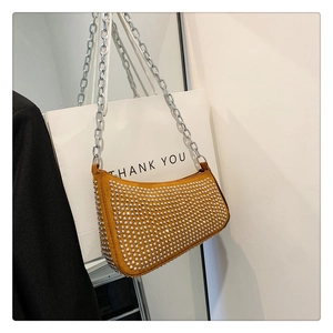 Close-up of mustard yellow leather bag featuring silver rivet studs and chain strap