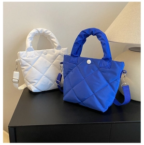 Detail of white and blue quilted nylon bucket bags showing stitch texture and snap closure