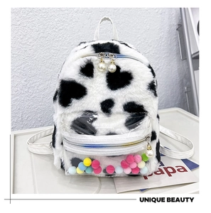 Détail du sac à dos en peluche à motif vache avec poche PVC et pompons colorés