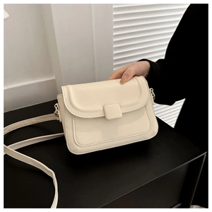 Detail of cream rectangular mini crossbody bag showing precise stitching and leather buckle