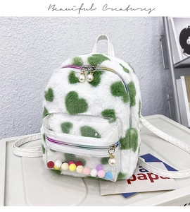 Détail du sac à dos en peluche blanche avec cœurs verts et pompons colorés dans la poche PVC