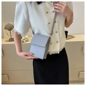 Détail d'un sac à bandoulière bleu minimaliste pour téléphone avec fermoir doré