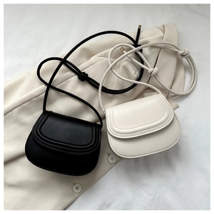 Detail of mini saddle cross-body bags in black and beige with knotted strap accents
