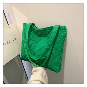 Detail of green quilted nylon tote bag with rhombus texture and matching wide strap