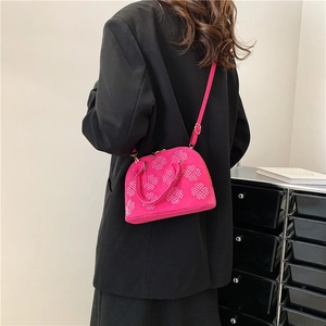 Sac bandoulière en daim fuchsia avec rivets argentés et détails dorés sur un modèle