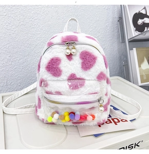 Détail d'un sac à dos en peluche blanche avec cœurs roses et poche transparente à pompons