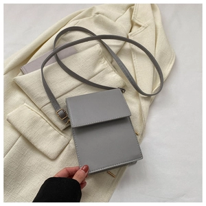 Détail du sac bandoulière gris minimaliste avec coutures fines et garnitures en métal doré
