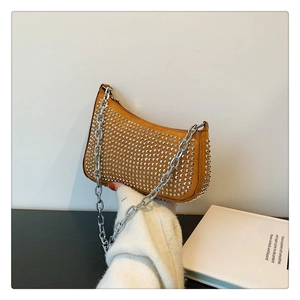 Detailed view of brown suede underarm bag featuring silver rivets and chunky metal chain