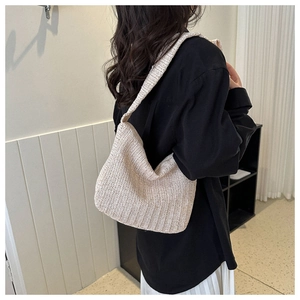 Close-up of cream woven straw tote bag showing vertical wave textures and wide shoulder strap