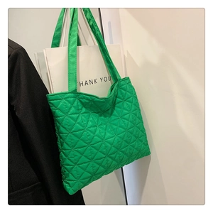 Detail view of large green quilted tote bag with triangle texture and long shoulder strap