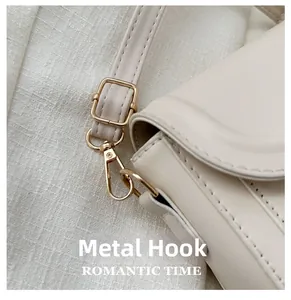 Detailed close-up of golden swivel hook and textured leather strap on a beige handbag