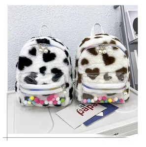 Détail de sacs à dos en peluche à motifs de cœur, zip arc-en-ciel et breloque perle